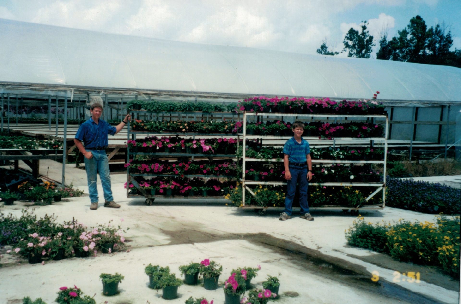Lester and his younger brother next to rack of plants