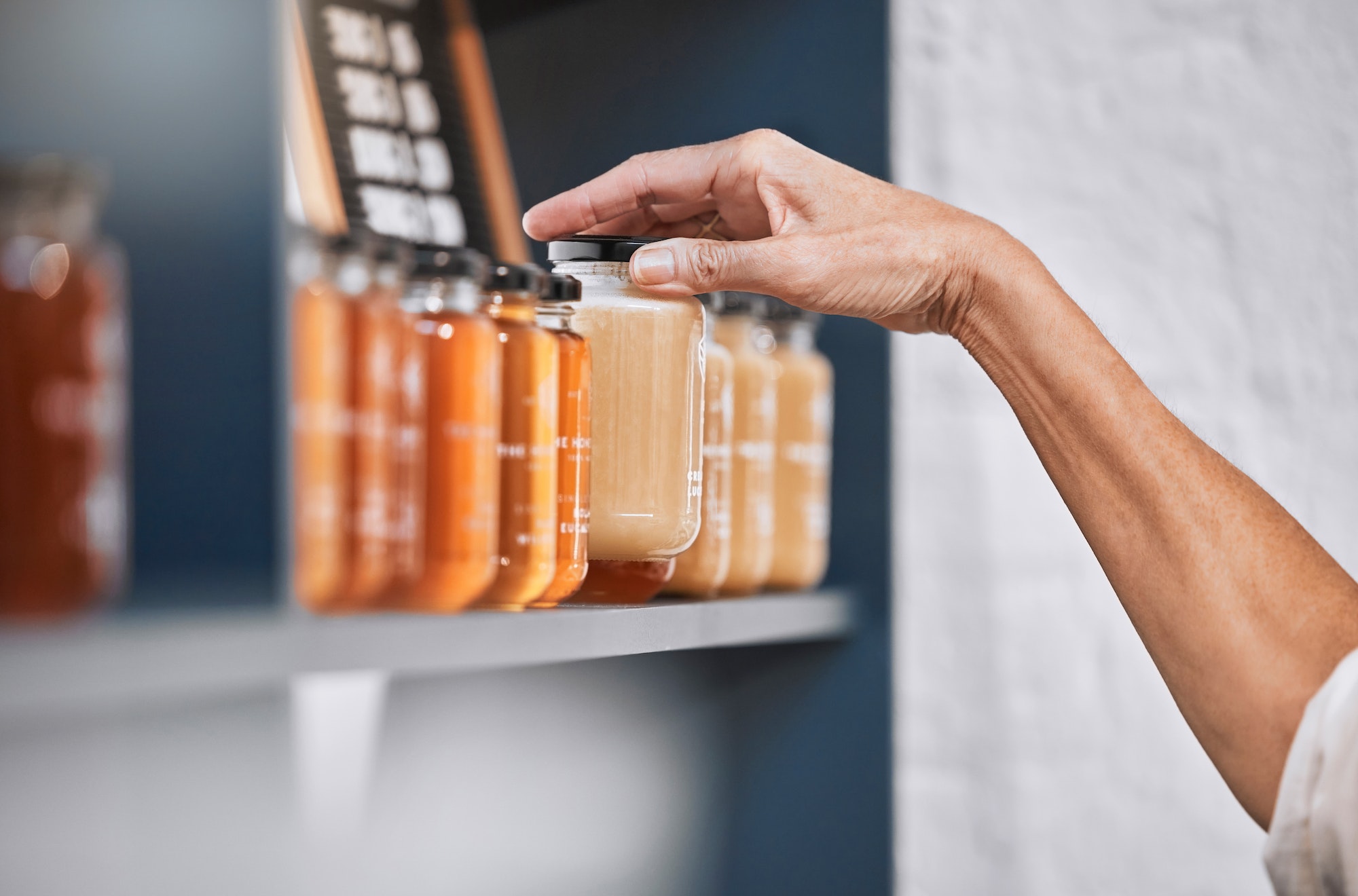 Honey, product and retail with hands of woman for natural, supermarket and grocery shopping shelf.